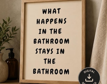 May include: A rectangular wooden frame containing a light beige print with the black text: WHAT HAPPENS IN THE BATHROOM STAYS IN THE BATHROOM. The frame is positioned on a shelf next to a brown bottle and a beige towel, with a digital download icon.