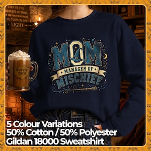 Könnte beinhalten: Ein marineblaues Sweatshirt mit Rundhalsausschnitt und einem grafischen Aufdruck MOM MANAGER OF MISCHIEF in blauen und goldenen Buchstaben. Das Design enthält einen Hexenhut, einen Zauberstab, Sterne und eine Mondsichel aus Baumwolle und Polyester.