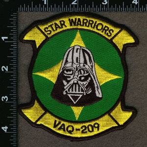 May include: A green and yellow embroidered patch with a black and white image of Darth Vader. The patch has the text "STAR WARRIORS" and "VAQ-209" on it.