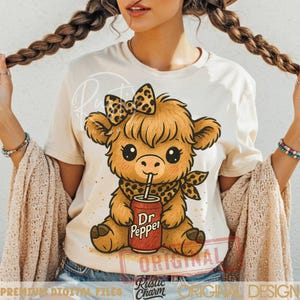 May include: Cream-colored t-shirt featuring a cartoon Highland cow with a leopard print bow, bandana, and a Dr. Pepper can. The design includes the text "Rustic Charm Original Design" and "Premium Digital Files".