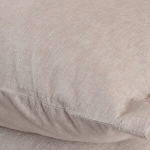 May include: Close-up of a beige pillowcase made of a soft, textured fabric. The fabric has a subtle woven pattern and a slightly rough feel.