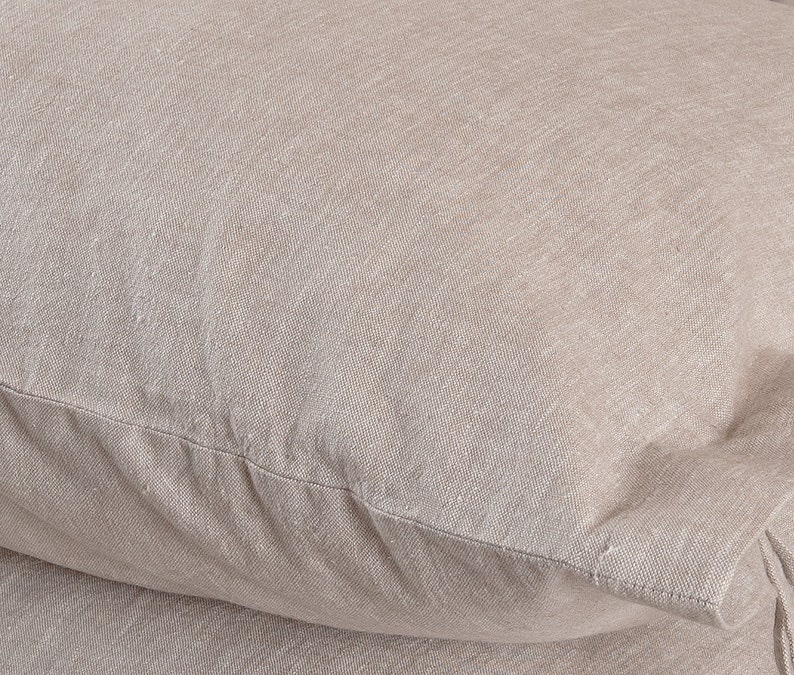 May include: Close-up of a beige pillowcase made of a soft, textured fabric. The fabric has a subtle woven pattern and a slightly rough feel.