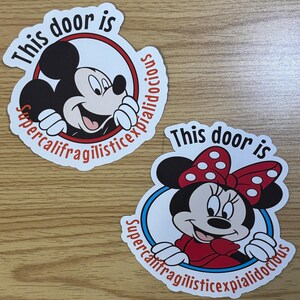 May include: Two round stickers featuring Mickey Mouse and Minnie Mouse. The stickers have a white background with a red circle around the characters. The text "This door is supercalifragilisticexpialidocious" is written around the circle. Mickey Mouse is wearing red shorts and yellow shoes. Minnie Mouse is wearing a red dress with white polka dots and a red bow.