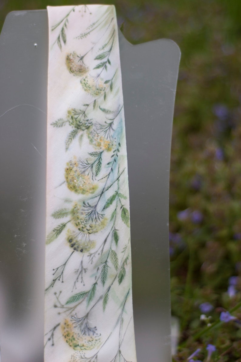 Puede incluir: Una corbata de seda blanca con un dise&ntilde;o de acuarela de hojas verdes y flores amarillas.