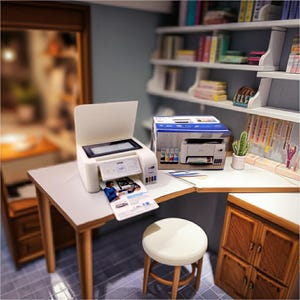 May include: Miniature white printer with a printed document emerging from the output tray. A box with the printer's image and ink cartridges sits nearby. The scene includes a small desk, stool, and a bookshelf, creating a dollhouse office setting.