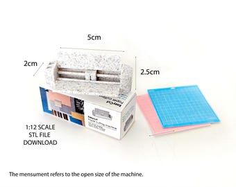 May include: A white paper cutter with a textured surface. The cutter is 5 cm long, 2.5 cm wide, and 2 cm tall. The cutter is on a box with the text "Easycut Paper Cutter" and "1:12 Scale STL File Download".
