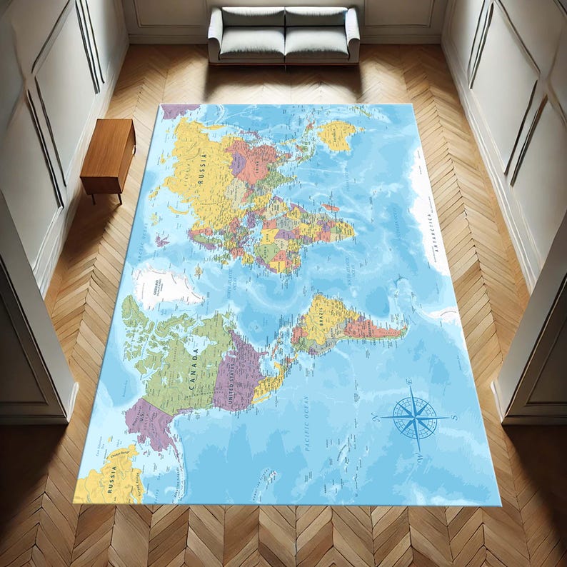 May include: A large rectangular rug featuring a detailed world map design. The rug displays continents in various colors against a blue ocean background. A compass rose is visible in the lower right corner. The rug is placed on a wooden floor.