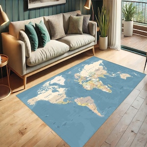 May include: A rectangular, blue area rug featuring a detailed world map design. The rug displays continents and countries in various colors, with ocean areas in shades of blue. The rug is placed on a wooden floor, near a sofa and a window.