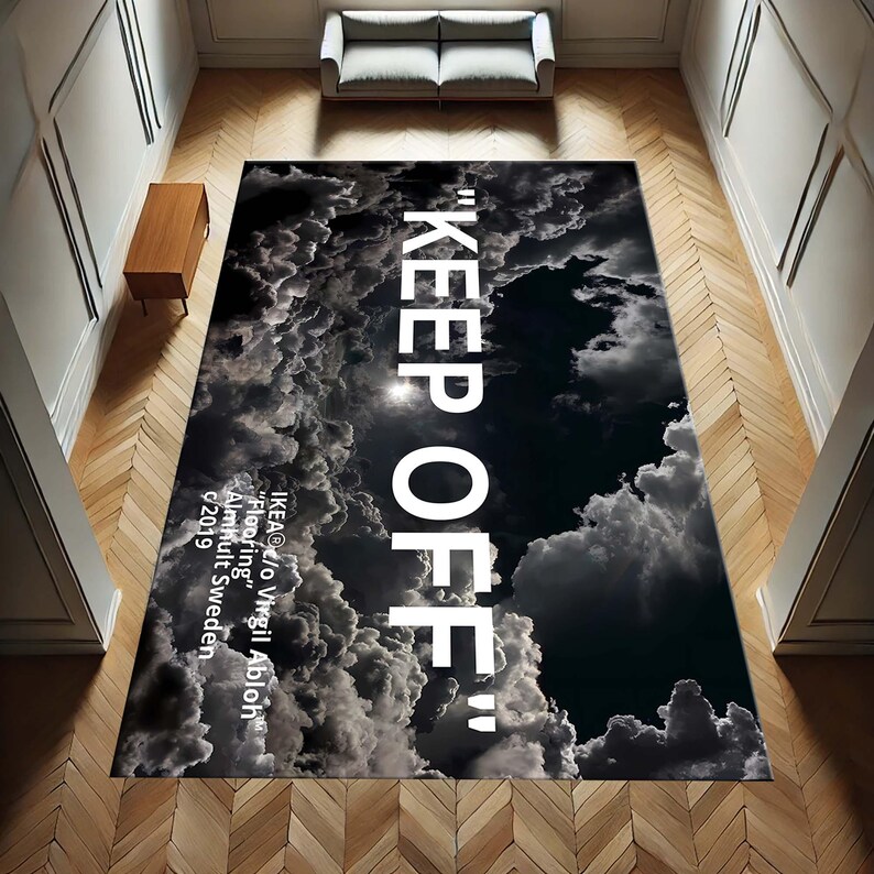 May include: Black and white rug with a cloud pattern and the text "KEEP OFF" in white. The text "IKEA@c/o Virgil Abloh" is printed in white at the bottom of the rug. The text "Flooring" is printed in white below the name. The text "Almhult Sweden" is printed in white below the text "Flooring". The text "2019" is printed in white below the text "Almhult Sweden".