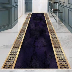 Puede incluir: Una alfombra de pasillo azul oscuro con bordes con patrones dorados. La alfombra tiene un aspecto desgastado y texturizado.
