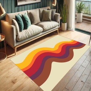 Pode incluir: Um tapete de cor creme com um design ondulado abstrato em tons de laranja, vermelho, marrom e roxo. O tapete est&aacute; colocado em um piso de madeira na frente de um sof&aacute;.