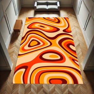 May include: Abstract area rug with a swirling pattern of orange, red, and brown. The rug has a cream-coloured background.