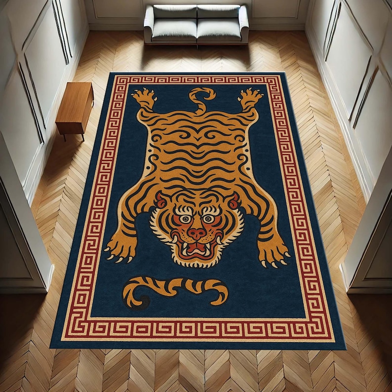 May include: A rectangular rug with a navy blue background features a stylized tiger design in shades of orange and black. The tiger is centered, surrounded by a red and gold Greek key border. The rug is placed on a wooden floor.