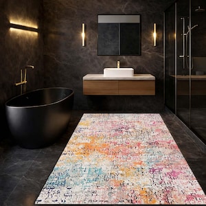 May include: A rectangular rug with a distressed design in a bathroom. The rug displays a blend of orange, pink, blue, and white shades. The bathroom includes a black bathtub, a wooden vanity, and a glass shower cubicle.