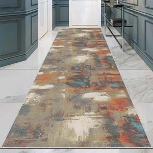 Può includere: Tappeto da area astratto con uno schema di colori beige, marrone, arancione e blu. Il tappeto ha un design moderno e astratto con forme grandi e irregolari.