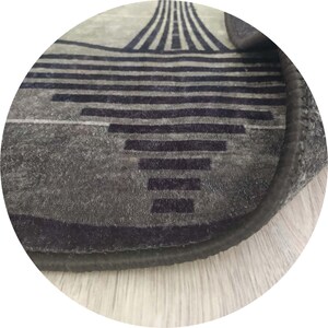 Pu&ograve; includere: Primo piano di un tappeto grigio con un design geometrico. Il tappeto presenta linee orizzontali e verticali blu scuro, creando un motivo moderno. I bordi sono rifiniti con un bordo scuro e il tappeto ha un aspetto morbido e strutturato.