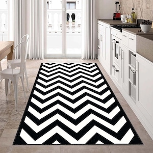 May include: Black and white chevron patterned area rug. The rug has a modern geometric design with alternating black and white stripes.