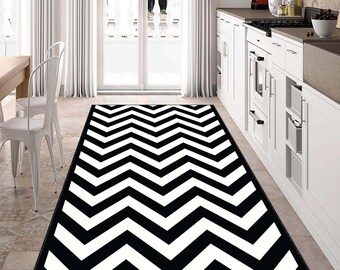 May include: Black and white chevron patterned area rug. The rug has a modern geometric design with alternating black and white stripes.