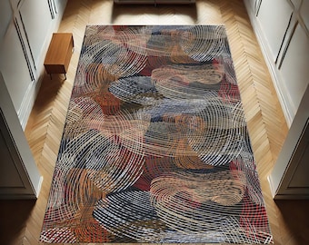 May include: A rectangular area rug with a swirling pattern in shades of black, brown, orange, and white. The rug's design features overlapping circular lines, creating a textured appearance. The rug is placed on a wooden floor.