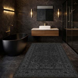 May include: A dark gray patterned rug in a modern bathroom setting. The rug is rectangular with an ornate design and is placed in front of a black bathtub. The bathroom features a wooden vanity, a white sink, and gold fixtures.