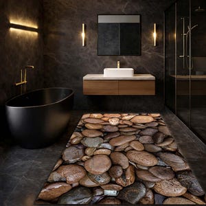 Op de afbeelding: Een moderne badkamer met een zwarte ligbad, een houten wastafel met een witte wastafel en een tapijt met steenpatroon. De muren zijn donkergrijs en de armaturen zijn goudkleurig. De douche is in glas ingesloten.
