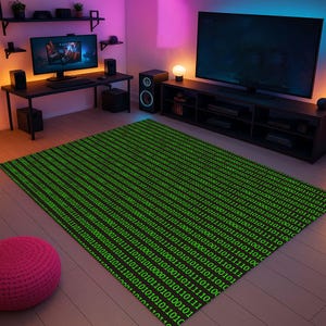 Op de afbeelding: Een groot rechthoekig vloerkleed met een zwarte achtergrond en een herhalend patroon van groene binaire code. Het vloerkleed ligt in een kamer met een computeropstelling, een tv en een roze poef.