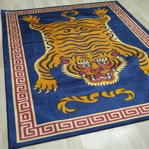 May include: A rectangular blue rug featuring a large, stylized tiger design in shades of orange, yellow, and black. The tiger is centered, with a detailed face and body. The rug has a decorative border in red and gold.