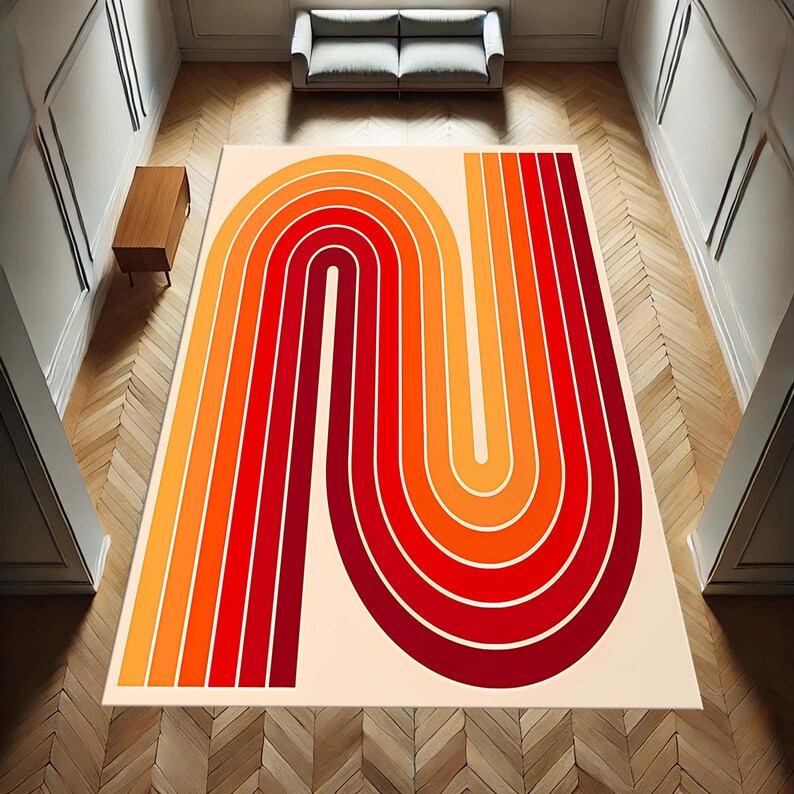 May include: A rectangular area rug with a retro design. The rug features a cream-colored background with a bold, abstract pattern in shades of red, orange, and yellow. The design resembles a stylized letter "N" or a rainbow.