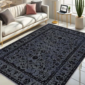 May include: A gray and black area rug with a floral pattern. The rug has a border with a repeating pattern.