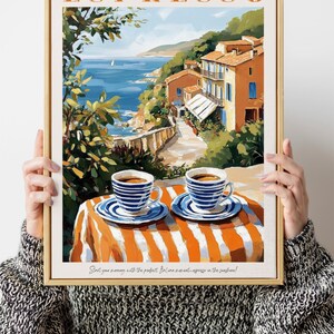May include: A framed poster with a painting of a coastal town in Italy. The poster has the word "ESPRESSO" in orange letters at the top. The painting shows a view of the town from a cafe table with two cups of espresso on the table. The text at the bottom of the poster reads "Start your morning with the perfect Italian moment - espresso in the sunshine!"