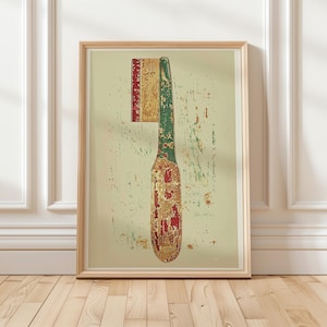 May include: Framed print featuring a vintage illustration of a comb. The comb is depicted in shades of red, green, and gold against a textured, off-white background. The artwork is encased in a light wooden frame, adding a touch of rustic charm.