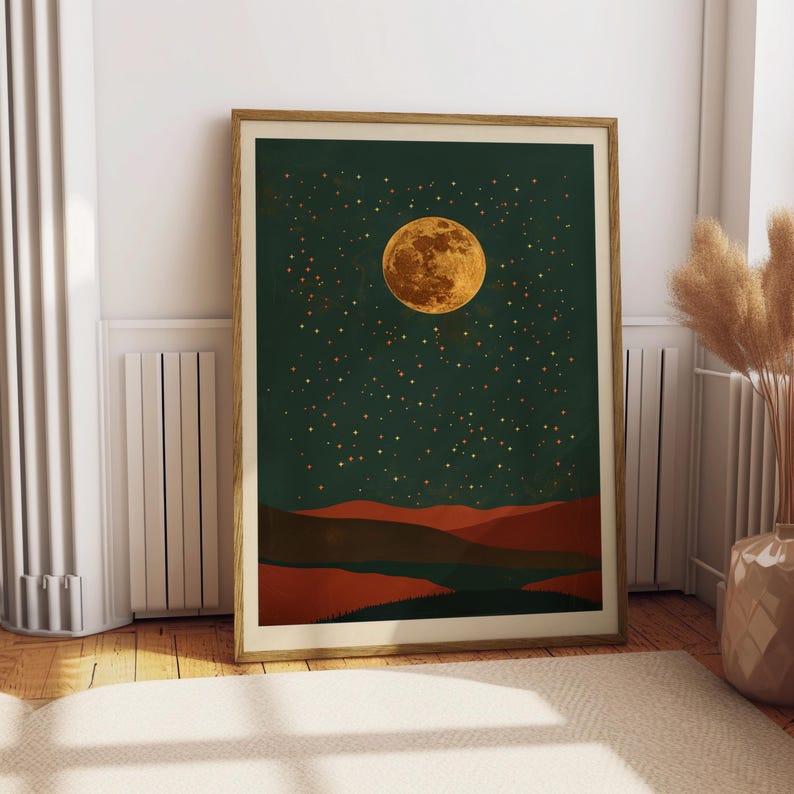 May include: Framed art print featuring a night landscape with a large, golden moon and a starry sky against a dark green background. The lower portion depicts reddish-brown hills. The artwork is in a wooden frame.