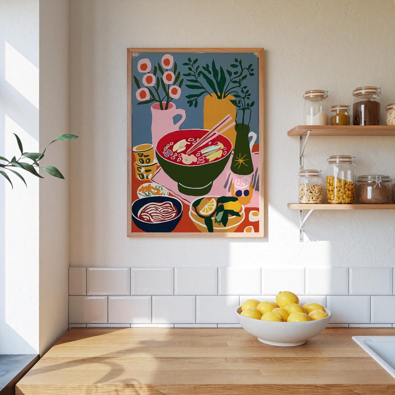 May include: A framed art print depicting a colorful still life of a ramen meal. The artwork features a large green bowl of ramen, chopsticks, and various side dishes. The background includes vases with flowers and plants, with a blue and orange color scheme.
