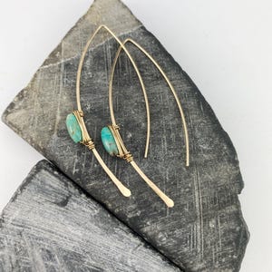 May include: A pair of gold earrings with turquoise stones. The earrings are long and thin, with a simple design.