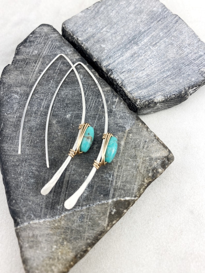 May include: A pair of silver dangle earrings with turquoise stones wrapped in gold wire.
