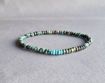 May include: A green and blue beaded bracelet with a turquoise accent.