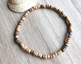 May include: A brown and beige wooden bead bracelet. The bracelet is made of small, round beads that are strung together on a thin cord.