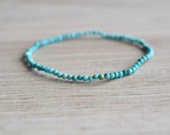 May include: A delicate turquoise beaded bracelet with small, round beads.