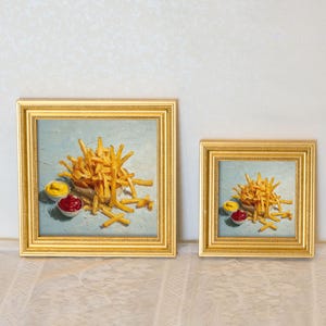 May include: Two framed square paintings show a still life of chips with ketchup and mustard. The chips are golden brown, and the condiments are in small white bowls. The frames are gold.