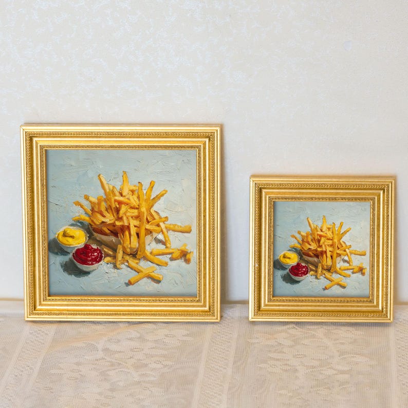May include: Two framed square paintings show a still life of chips with ketchup and mustard. The chips are golden brown, and the condiments are in small white bowls. The frames are gold.