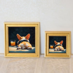 K&ouml;nnte beinhalten: Zwei gerahmte Kunstdrucke mit einem Corgi-Hund mit einem Getr&auml;nk. Der Corgi liegt, von hinten gesehen, mit einem schwarzen Halsband. Das Kunstwerk hat einen dunklen Hintergrund und ein Glas bernsteinfarbener Fl&uuml;ssigkeit. Die Rahmen sind goldfarben.