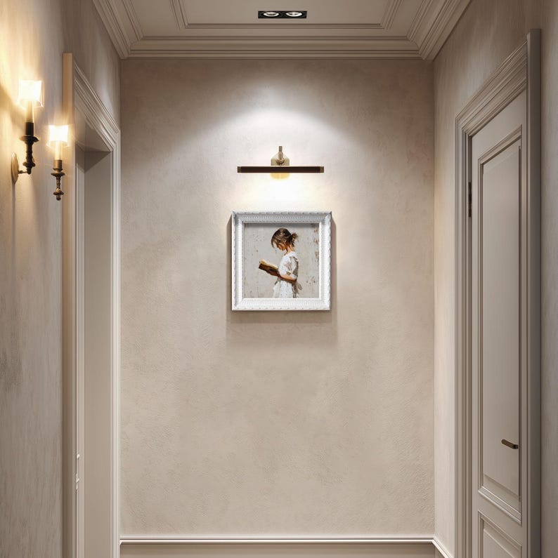 Pu&ograve; includere: Un corridoio con una palette di colori neutri, con un quadro incorniciato di una ragazza che legge, un'applique e un'applique. Il dipinto &egrave; centrato sulla parete, con una porta a destra e una porta a sinistra.