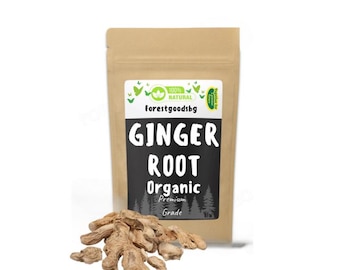 Op de afbeelding: Een bruine papieren zak met biologische gemberwortel. De zak heeft de tekst "Ginger Root Organic Premium Grade" op een zwart label. Een hoop gemberwortel ligt voor de zak. De zak heeft de tekst "100% Natural" en het merk "forestgoodsbg".