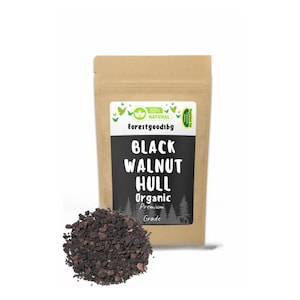 Può includere: Un sacchetto di carta color marrone chiaro con l'etichetta Forestgoodsbg contenente mallo di noce nera biologico di qualità premium, con un mucchio di frammenti di mallo di noce marrone scuro, grossolani, davanti alla confezione.