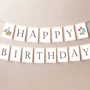 May include: A banner with the words "HAPPY BIRTHDAY" in dark brown letters. The letters are on individual cream-colored square flags with a light brown checkered pattern. The banner is strung on a thin brown string. The flags have cartoon illustrations.