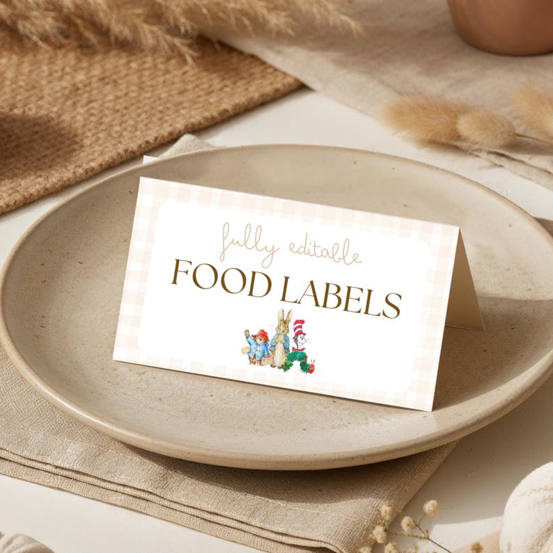 May include: A folded white card with a light pink gingham border featuring the text fully editable FOOD LABELS in brown font. Below the text are small watercolor illustrations of Paddington Bear, Peter Rabbit, and The Cat in the Hat.