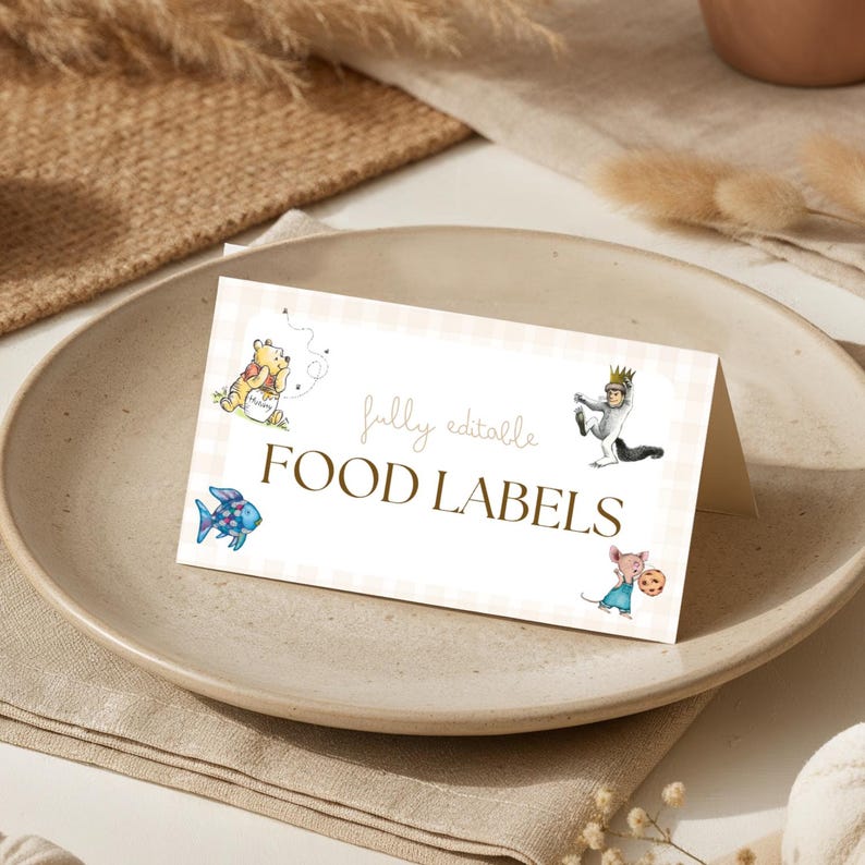 May include: A folded food label card with a beige gingham pattern. The card features illustrations of cartoon characters and the words "fully editable FOOD LABELS". The card is displayed on a ceramic plate.