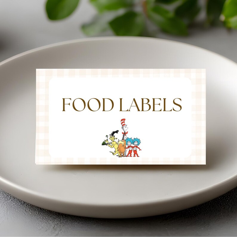 May include: A rectangular food label with the words "FOOD LABELS" in brown font. The label has a light beige checkered background and features cartoon characters at the bottom. The label is on a white plate.