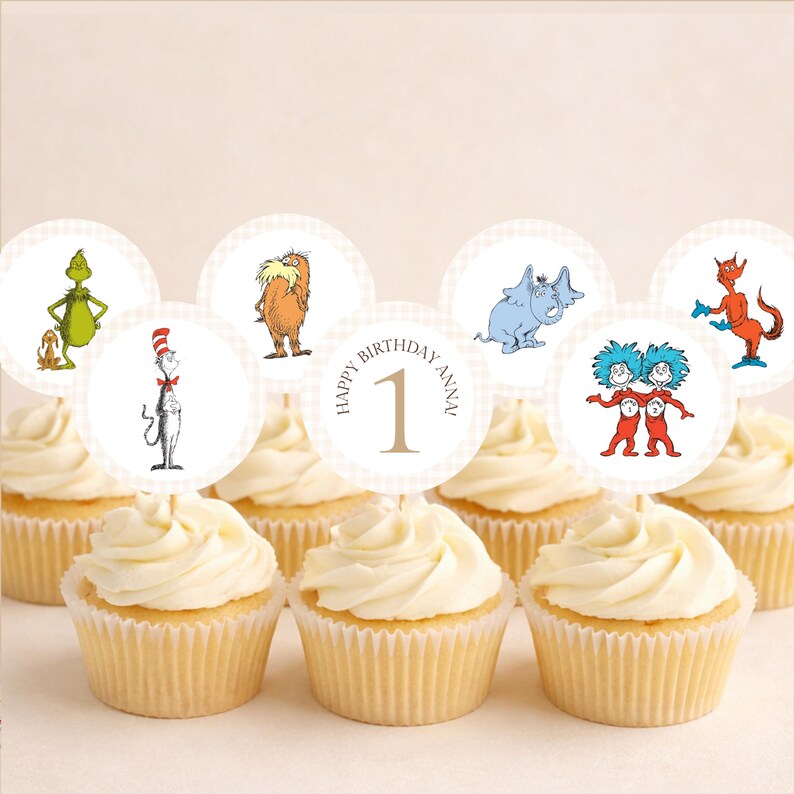 May include: Cupcakes topped with circular decorations featuring Dr. Seuss characters, including the Grinch, the Cat in the Hat, and Thing 1 and Thing 2. The decorations are on a light beige background, with the text "HAPPY BIRTHDAY ANNA 1".