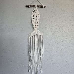 May include: A white ceramic mug with a black handle and the text "But First, Coffee" in a black, handwritten-style font. The mug is on a white surface.